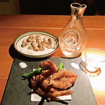 Small blowfish karaage (front) served with cold sake and roasted ginkgo nuts (back).